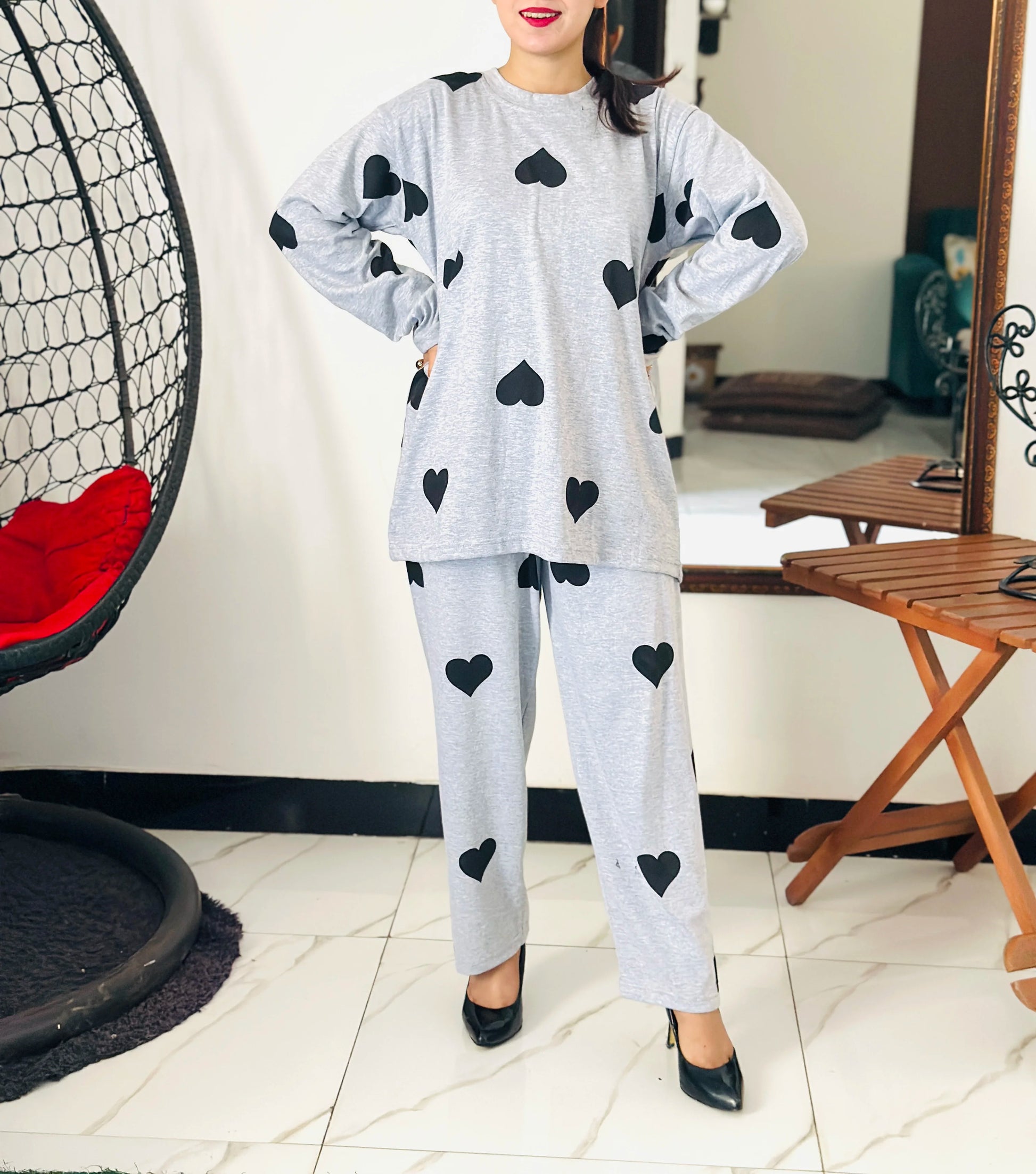 Person wearing a gray outfit with black heart patterns in a room.